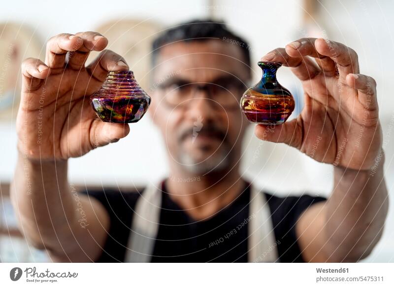 Close-up of male artist holding miniature vases in workshop color image colour image Spain indoors indoor shot indoor shots interior interior view Interiors