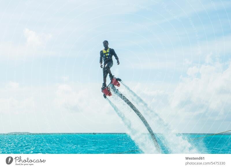 Maldives, man on flyboard above the sea Flyboard ocean men males water waters body of water Adults grown-ups grownups adult people persons human being humans