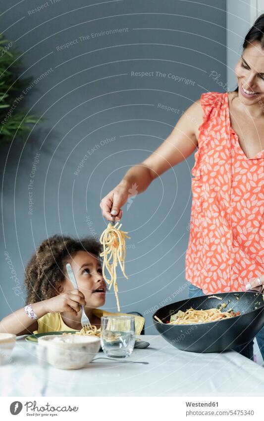 Mother serving pasta meal for daughter sitting at dining table human human being human beings humans person persons caucasian appearance caucasian ethnicity