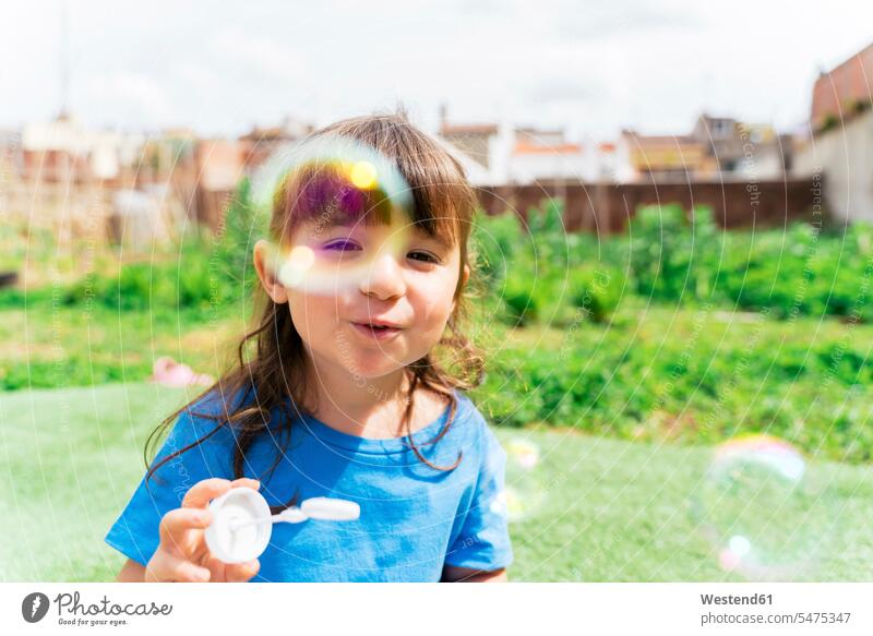 Portrait of happy little girl blowing soap bubbles in a park T- Shirt t-shirts tee-shirt fly smile seasons spring season Spring Time springtime summer time