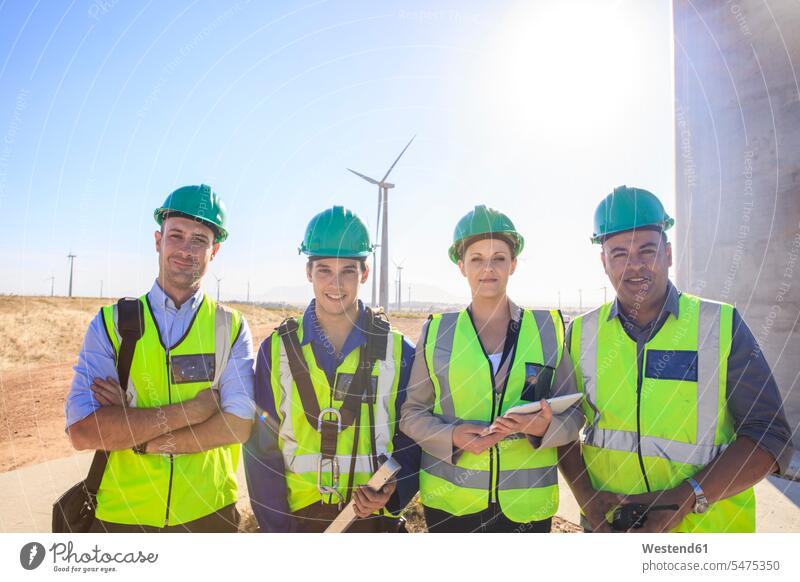 Portrait of four smiling engineers on a wind farm wind park smile portrait portraits wind power plant wind turbine wind turbines wind energy renewable energy