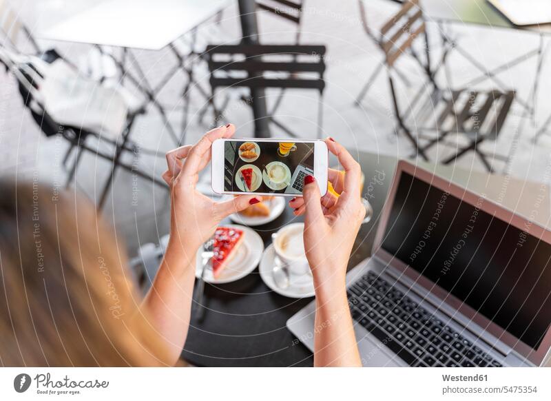 Young blogger sitting at street cafe taking photo of food, partial view human human being human beings humans person persons caucasian appearance