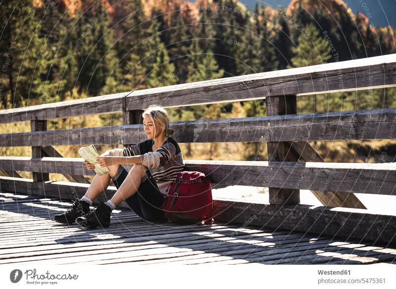 Austria, Alps, young woman with backpack sitting on bridge taking a break caucasian caucasian appearance caucasian ethnicity european White - Caucasian