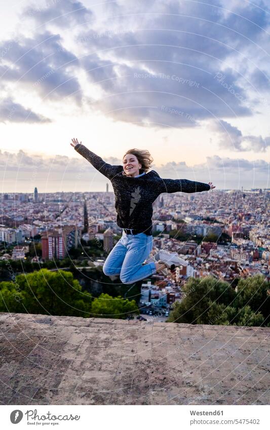 Carefree young woman jumping above the city at sunrise, Barcelona, Spain human human being human beings humans person persons caucasian appearance