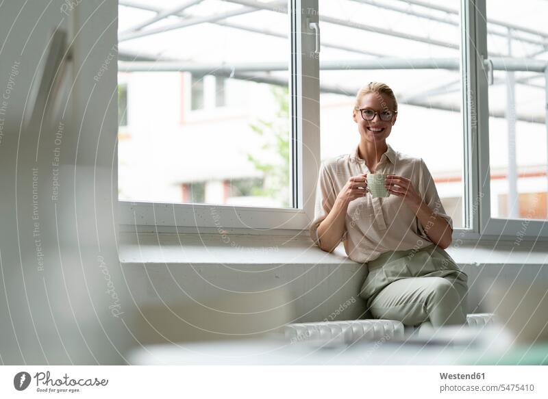 Portrait of smiling young businesswoman with cup of coffee sitting at the window Occupation Work job jobs profession professional occupation business life