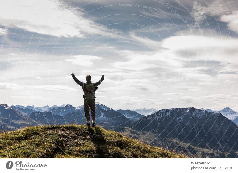 Austria, Tyrol, young man standing in mountainscape cheering mountain range mountain ranges jubilate rejoicing rejoice exultation jubilating hiking hike men