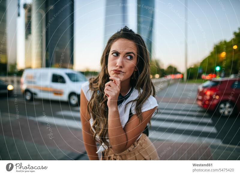 Young woman with doubtful face, skyscrapers in the background human human being human beings humans person persons caucasian appearance caucasian ethnicity
