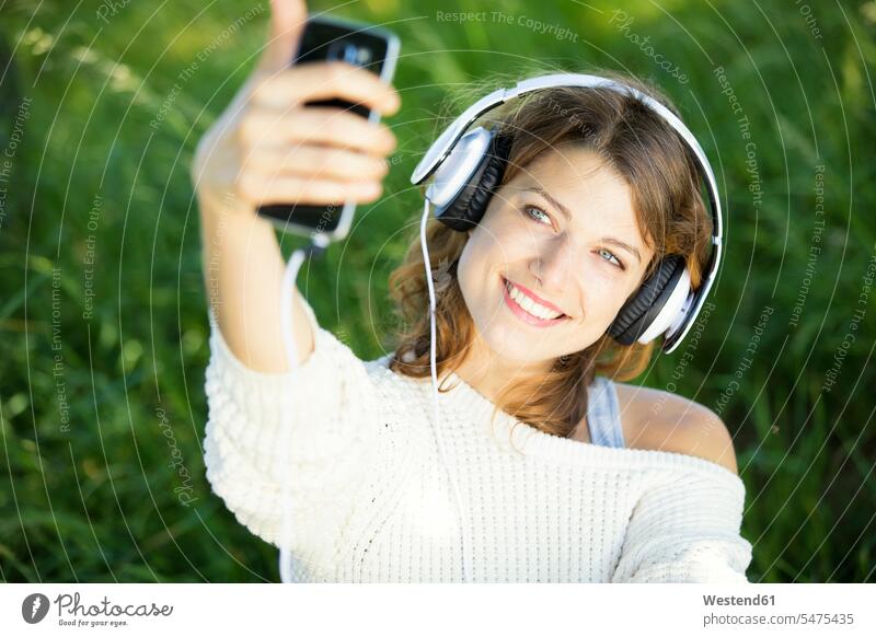 Smiling young woman with earphones taking a selfie smiling smile headphones headset music Selfie Selfies Smartphone iPhone Smartphones photographing females