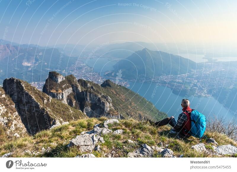 Rear view of hiker sitting on mountaintop, Orobie Alps, Lecco, Italy human human being human beings humans person persons caucasian appearance