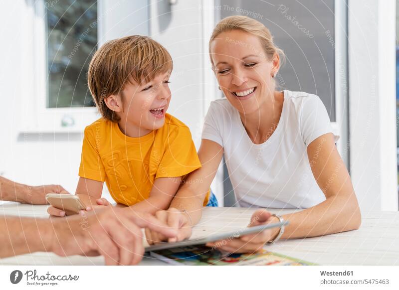 Happy mother and son doing homework and using tablet together on terrace pupils schoolchild schoolchildren T- Shirt t-shirts tee-shirt Tables smile Seated sit