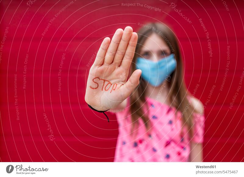 Girl with face mask showing palm of her hand, saying stop colour colours at home gesturing protect protecting safe Safety secure stopping walls location shot
