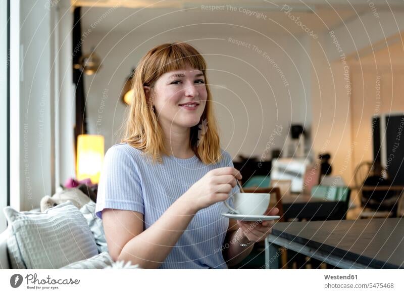 Portrait of strawberry blonde young woman with nose piercing with cup of coffee in a cafe human human being human beings humans person persons