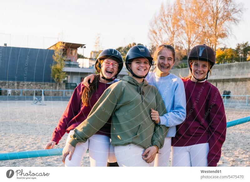 Portrait of cheerful female jockeys standing together at training ground against sky color image colour image equestrian sports horse riding equistry equitation
