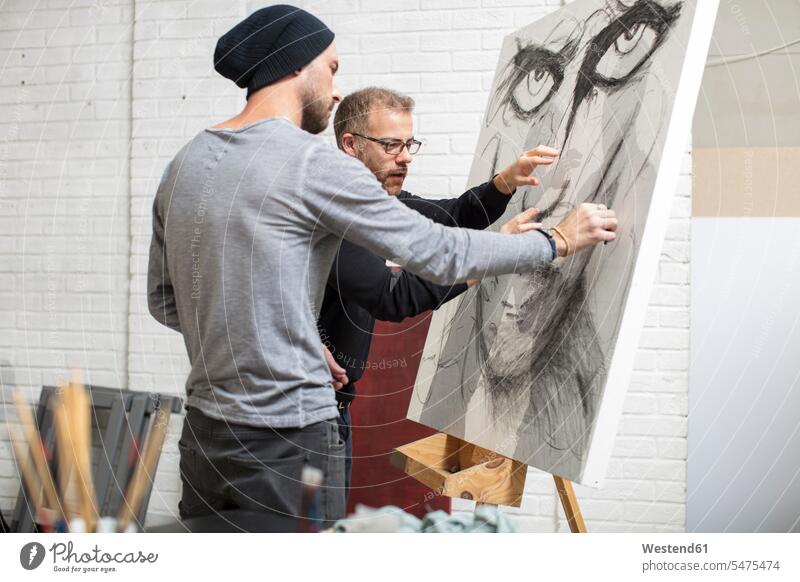 Artist discussing drawing with man in studio discussion studios drawings men males artist artists image images picture pictures Adults grown-ups grownups adult