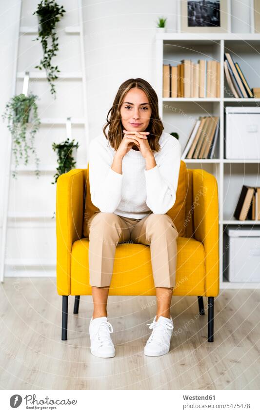 Smiling businesswoman sitting with head in hands on sofa at office color image colour image indoors indoor shot indoor shots interior interior view Interiors