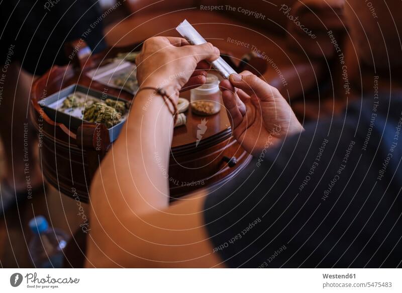 Close-up of a hands rolling a joint of marijuana Tables wood wood table relax relaxing hold at home Social Issue Social Theme Social Themes Social Topic