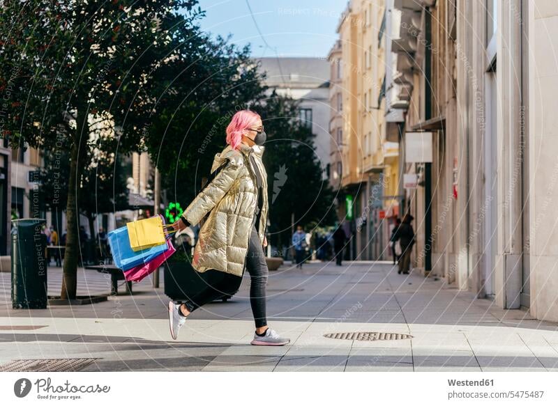 Woman wearing face mask running with shopping bags on footpath in city color image colour image outdoors location shots outdoor shot outdoor shots day