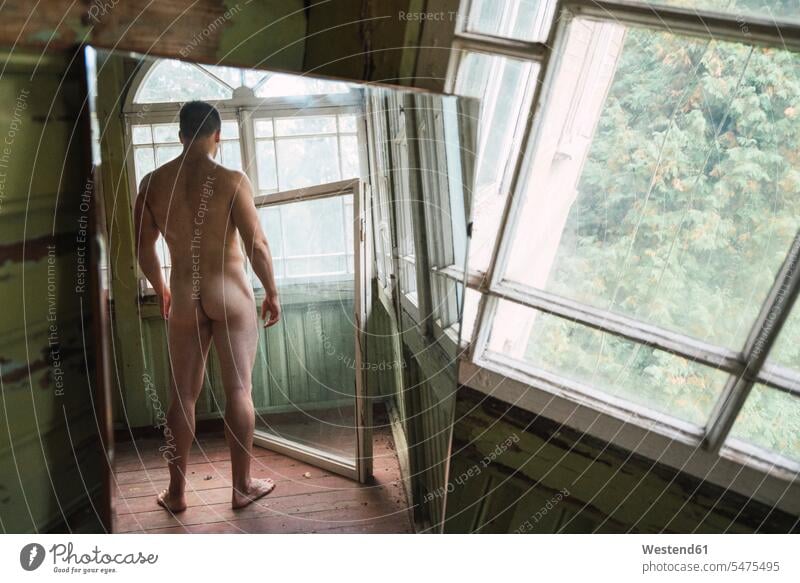 Mirror image of naked man standing at window of abandoned house houses Nudeness Nudity undressed nude bare men males Abandoned windows mirror image reflexion