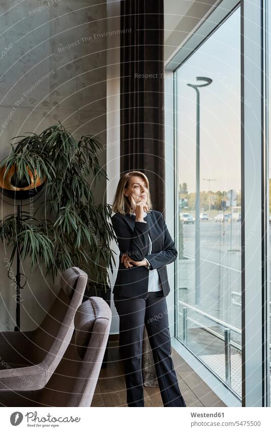 Thoughtful woman looking through window while standing in hotel lobby color image colour image indoors indoor shot indoor shots interior interior view Interiors