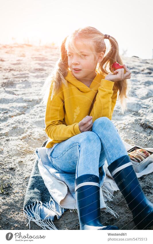 Portrait of girl with plaits sitting on the beach in autumn eating an apple Apple Apples portrait portraits beaches females girls fall braid braids Seated Fruit