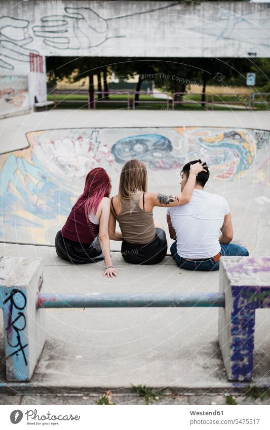 Rear view of friends sitting in skatepark Seated Skateboard Park skate park parks friendship togetherness lifestyle life styles Hand In Hair Hands In Hair