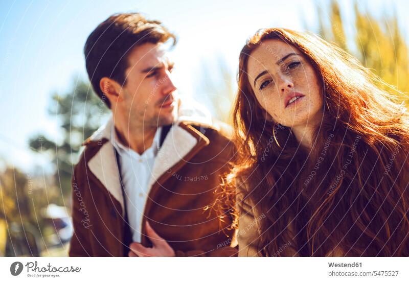 Young woman with thoughtful man in background during sunny day color image colour image outdoors location shots outdoor shot outdoor shots daylight shot