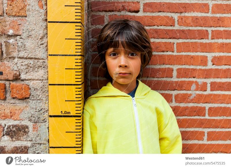 Portrait of sceptical boy leaning against yardstick boys males portrait portraits scepticism yardsticks child children kid kids people persons human being