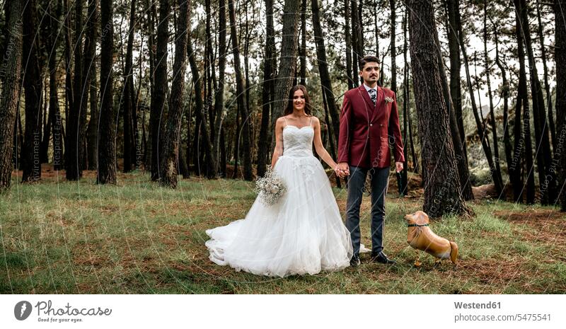Happy bride and groom standing in forest with funny dog-shaped balloon brides Wedding getting married marrying Marriage dogs woods forests bridal couple