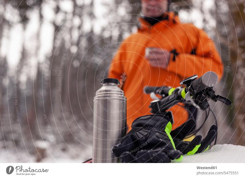 Man having a break from mountainbike trip in winter forest having a hot drink excursion Getaway Trip Tours Trips mountain biker Mountain Bikers woods forests