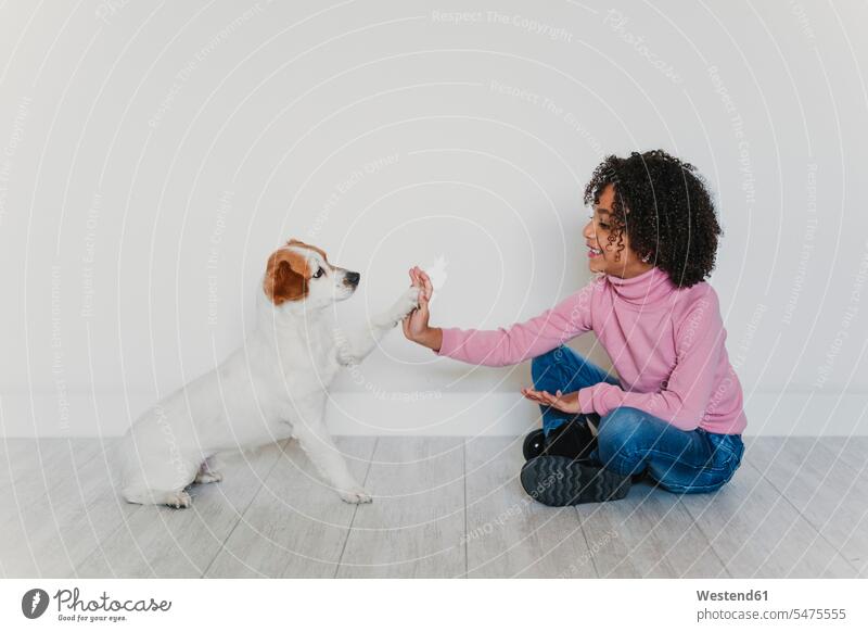 Smiling little girl sitting on the floor with her dog giving paw human human being human beings humans person persons 1 one person only only one person children