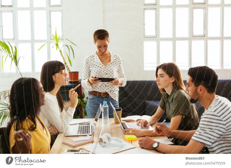 Colleagues working together at desk in office desks business people businesspeople smiling smile offices office room office rooms colleagues At Work Table