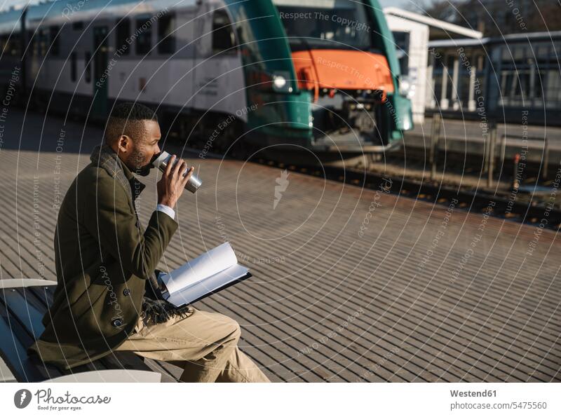 Stylish businessman drinking hot drink from reusable cup while waiting for the train Occupation Work job jobs profession professional occupation business life