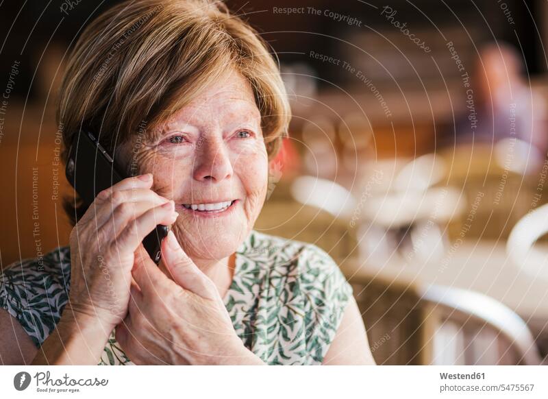 Smiling woman talking on mobile phone while sitting at cafe color image colour image indoors indoor shot indoor shots interior interior view Interiors