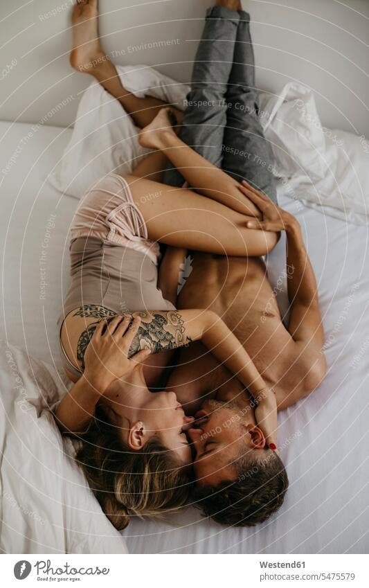 Romantic young couple lying in bed beds romantic lyrical Romance laying down lie lying down twosomes partnership couples people persons human being humans