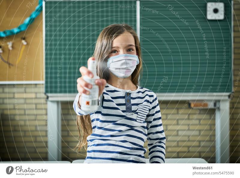 Portrait of girl wearing mask in classroom spraying sanitizer pupils schoolchild schoolchildren blackboards healthy protect protecting safe Safety secure