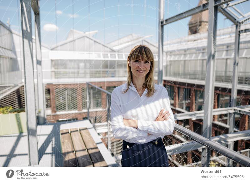 Smiling female professional with arms crossed standing in greenhouse color image colour image Germany business people businesspeople Business Professional