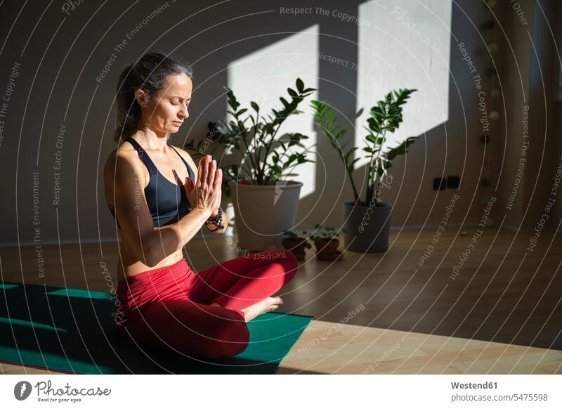 Yogini with eyes closed doing prayer pose at home on sunny day color image colour image indoors indoor shot indoor shots interior interior view Interiors