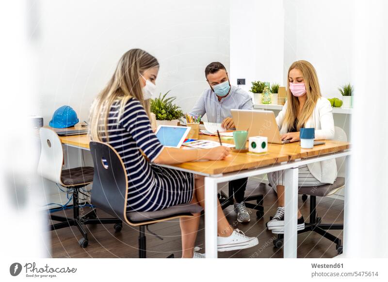 Business people wearing face mask while sitting by desk at office color image colour image indoors indoor shot indoor shots interior interior view Interiors day