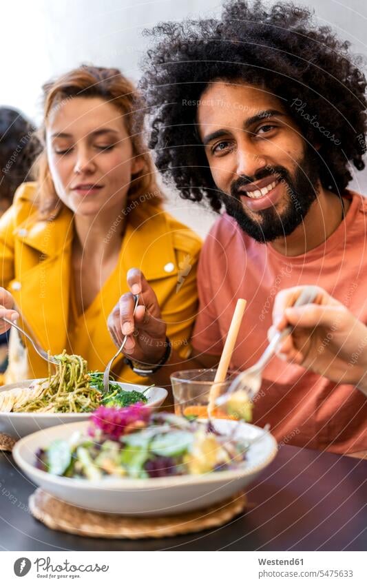 Friends having lunch in a restaurant Drinking Glass Drinking Glasses dish dishes Plates flatware Forks Tables smile Seated sit delight enjoyment Pleasant