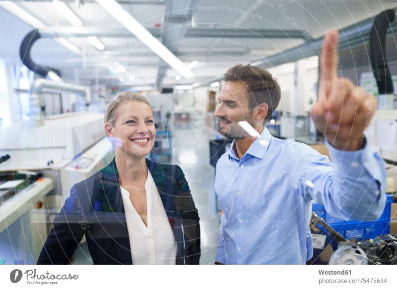 Young male technician pointing at graphical interface on glass in factory color image colour image indoors indoor shot indoor shots interior interior view