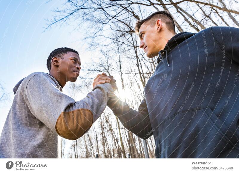 Two sportive young men shaking hands outdoors sporting sporty athletic Handclasp Handclap friends mate sports handshake friendship sky skies training