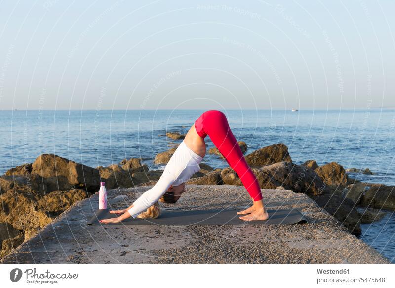 Young woman practicing yoga on the beach, doing downward facing dog exercise exercising practice practise practising in the morning flexible Force Power