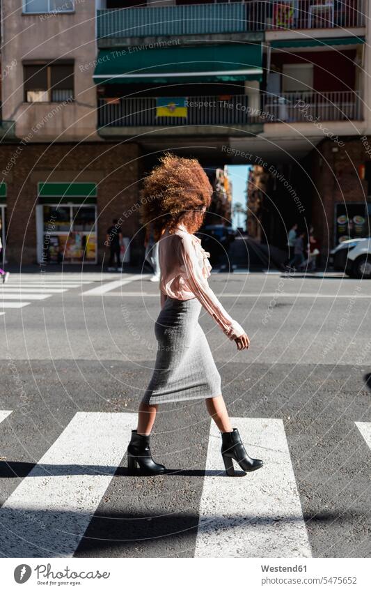 Young woman with afro hairdo crossing the street in the city road streets roads Barcelona obscured face obscured faces face hidden unrecognisable person