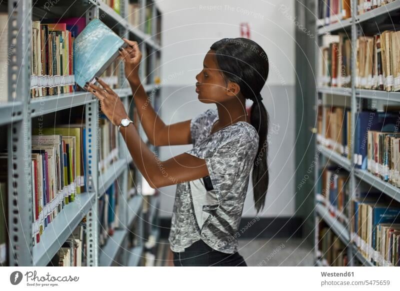 Young woman checking the books at the bookshelves at National library, Maputo, Mocambique human human being human beings humans person persons African black