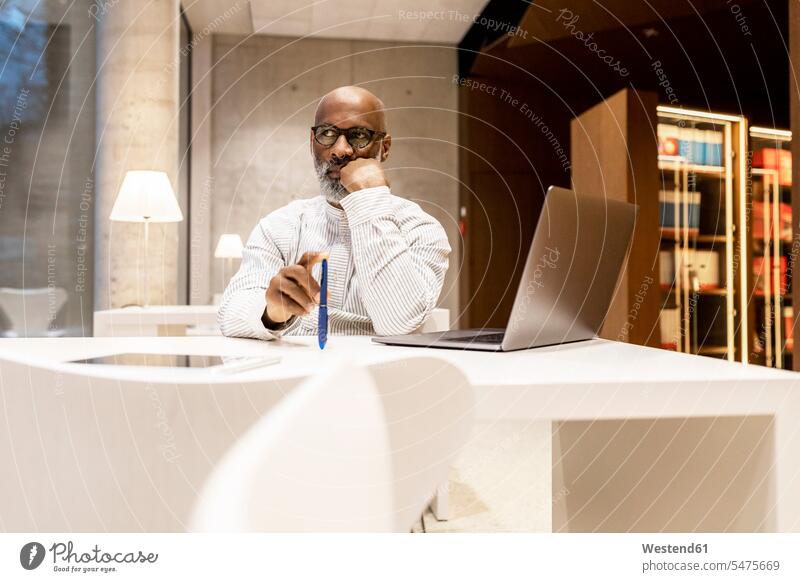 Portrait of pensive man sitting at library in the evening Businessman Business man Businessmen Business men thoughtful Reflective contemplative Seated males