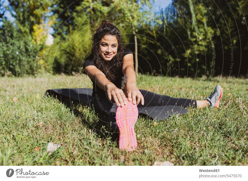 Sporty young woman stretching her leg on a meadow legs human leg human legs meadows sportive sporting sporty athletic females women people persons human being