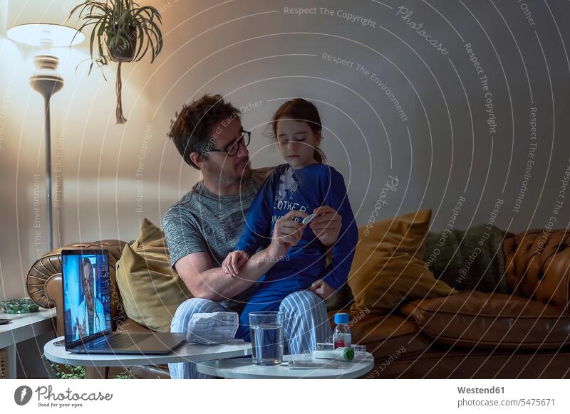 Man holding thermometer while sitting with sick daughter during video call at home color image colour image Home Interior Home Interiors domestic space indoors