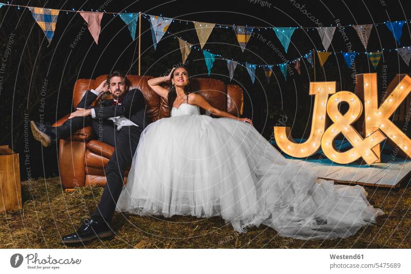 Portrait of wedding couple posing sitting on sofa on a night field party Wedding getting married marrying Marriage portrait portraits Seated Party Parties