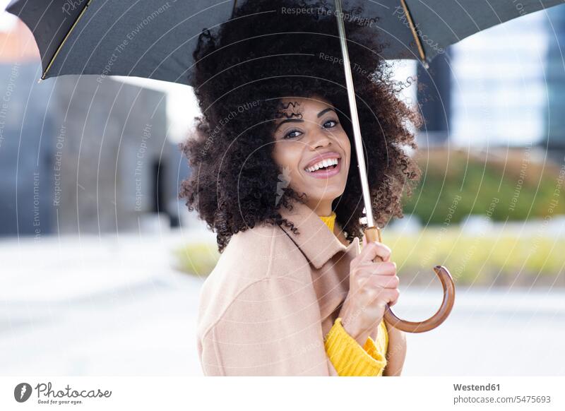 Smiling woman wearing jacket holding umbrella while standing outdoors color image colour image location shots outdoor shot outdoor shots day daylight shot