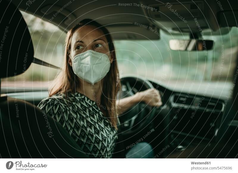 Mid adult woman with protective mask in car motor vehicles road vehicle road vehicles Auto automobile Automobiles cars motorcar motorcars drive motoring Seated